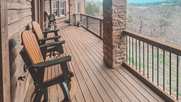 Una terraza de madera con sillas Adirondack, un pilar de piedra y vistas del paisaje.