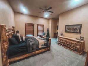 A bedroom with a wooden bed, a ceiling fan, a dresser, and a framed picture on the wall. - Spacious 5-bedroom house in peaceful Branson with AC (Branson)