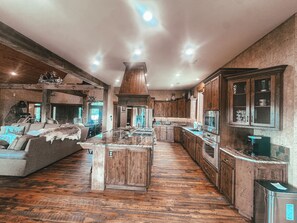 A spacious kitchen with wooden cabinets, a central island, and a dining area with a sofa. - Spacious 5-bedroom house in peaceful Branson with AC (Branson)