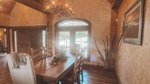 Un comedor con mesa de madera, sillas y una lámpara de araña.