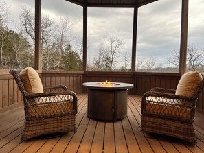 A covered outdoor seating area with wicker chairs and a central fire pit. - Spacious 5-bedroom house in peaceful Branson with AC (Branson)