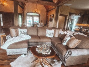 A cozy living room with a sectional sofa, a coffee table with decorative items, and a rustic wooden ceiling. - Spacious 5-bedroom house in peaceful Branson with AC (Branson)
