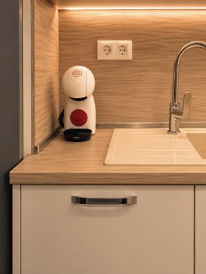 Et moderne køkken med indbygget vask, kaffemaskine og stikkontakt.