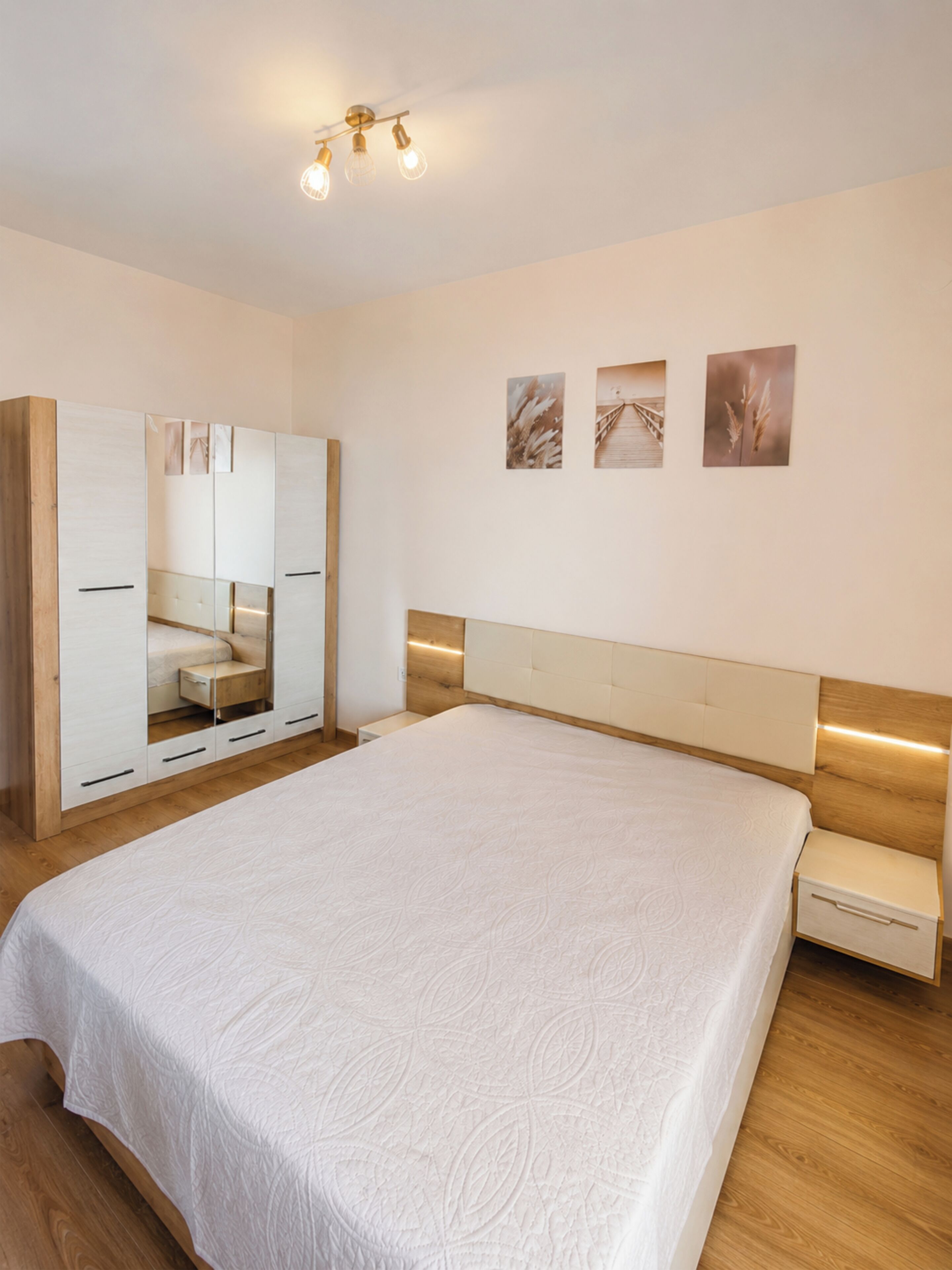 A bedroom with a large bed, a wardrobe, and a nightstand.