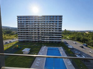 Et hotel med flere etager, en swimmingpool og en parkeringsplads.