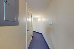 Ein schmaler Flur mit einer Tür links und einem Lichtschalter rechts.
