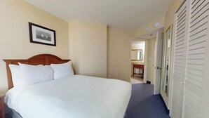 Ein Hotelzimmer mit einem großen Bett, einem Holz-Kopfteil, einem gerahmten Bild an der Wand und einem Schrank mit Schiebetüren.