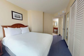 Ein Hotelzimmer mit einem großen Bett, einem Holz-Kopfteil, einem gerahmten Bild an der Wand und einem Schrank mit Schiebetüren.