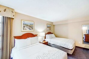 A hotel room with two beds, a nightstand with a lamp, and two framed pictures on the wall. - Carolinian Beach Resort 0430 (Myrtle Beach)