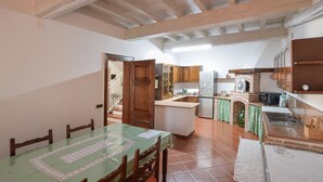 A kitchen with wooden cabinets, a tiled floor, and a dining area with a table and chairs.