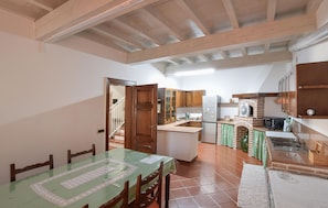 A kitchen with wooden cabinets, a tiled floor, and a dining area with a table and chairs.
