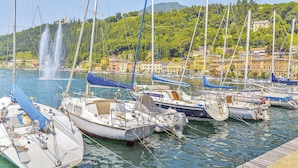 A marina with boats docked, a fountain in the background, and buildings with balconies overlooking the water.