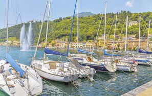 A marina with boats docked, a fountain in the background, and buildings with balconies overlooking the water.