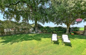 A backyard with two white lawn chairs, a hammock, and a swing set. - Stunning home in Goito with WiFi (Goito)