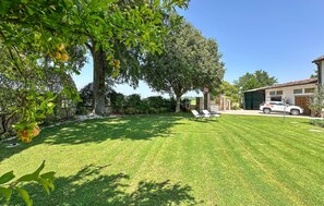 A well-maintained lawn with a large tree and a parked car in a residential setting. - Stunning home in Goito with WiFi (Goito)