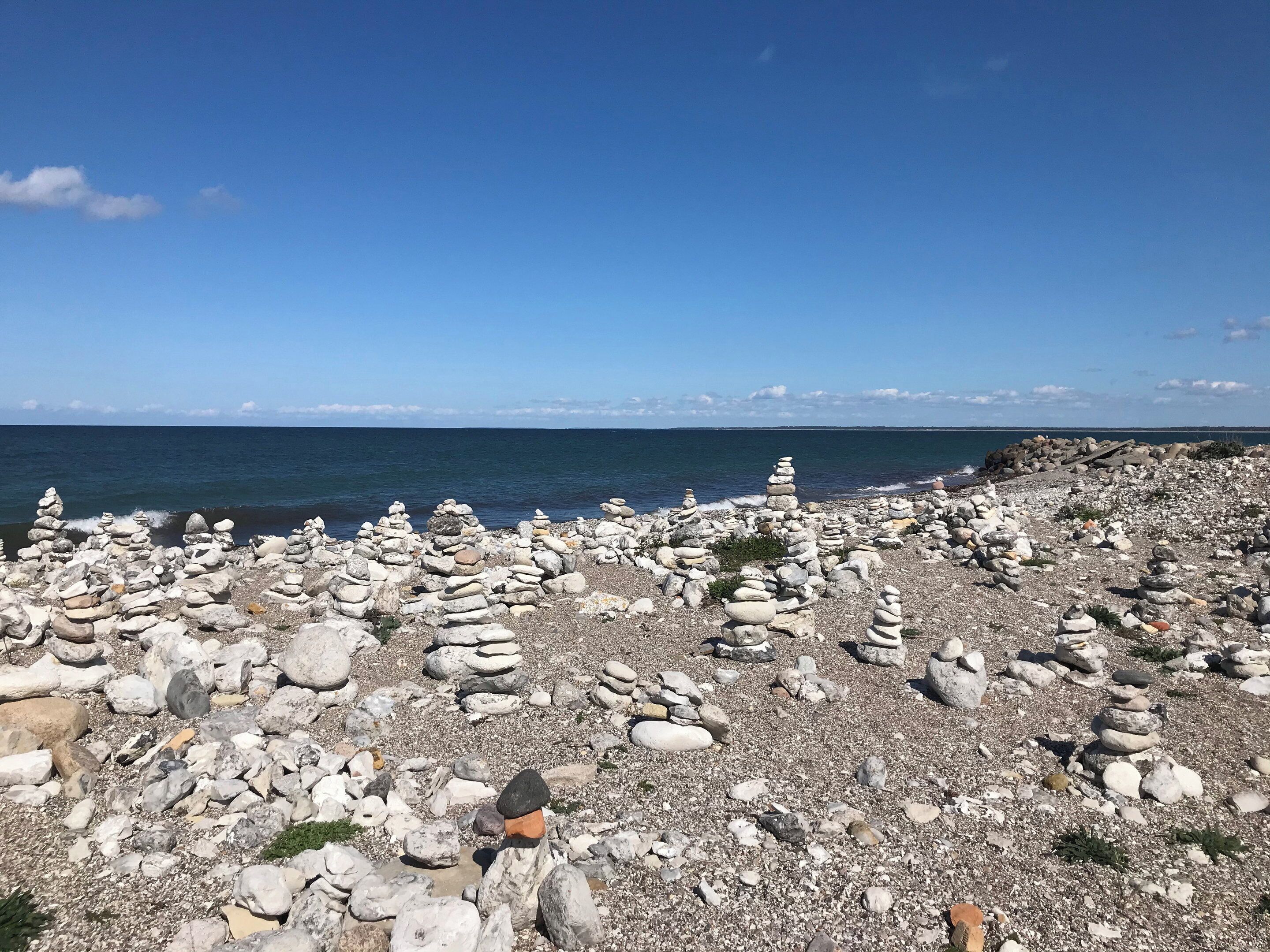 Ein felsiger Strand mit Steinaufgeschichten und freiem Blick auf das Meer.