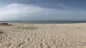 En strand med en rød båd, klar himmel og roligt hav.