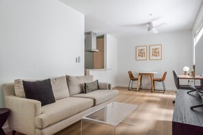 Uma sala de estar moderna com sofá, mesa de centro, mesa de jantar, cadeiras e um ventilador de teto.
