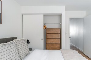 Ein Schlafzimmer mit einem Bett, einem Kleiderschrank und einer Tür zu einem anderen Raum.