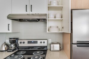 A modern kitchen with white cabinets, a stainless steel stove, a coffee maker, and a toaster. - Blueground | Denny Triangle, gym, nr Seattle Art Museum (Seattle)
