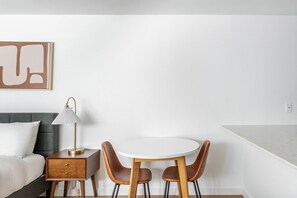 A hotel room with a bed, bedside table, lamp, and a round dining table with two chairs. - Blueground | Denny Triangle, gym, nr Seattle Art Museum (Seattle)