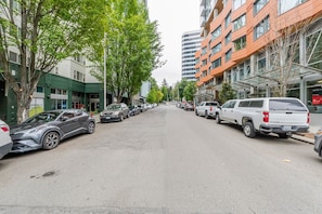 A street lined with parked cars and buildings, including a hotel with a green facade and a restaurant with outdoor seating. - Blueground | Denny Triangle, gym, nr Seattle Art Museum (Seattle)