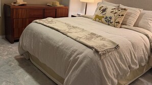 Una camera da letto con un letto grande, una cassettiera in legno, uno specchio tondo e una finestra con tende.