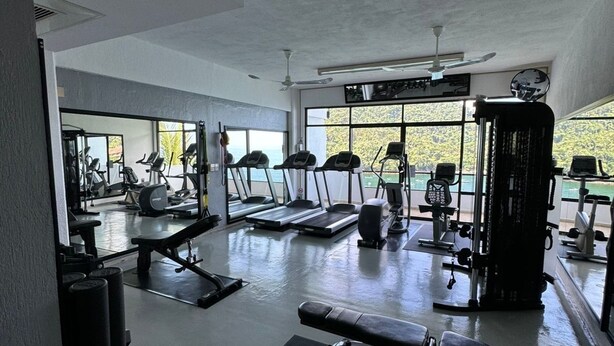 A gym with treadmills, weight machines, and exercise mats. - Located right on the water! Modern 1-bedroom condo in tranquil Mismaloya  (Mismaloya)