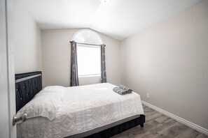 A bedroom with a bed, a window with curtains, and a door. - Serene 5-bedrooms 3 bathrooms House with Pool in North Las Vegas (North Las Vegas)
