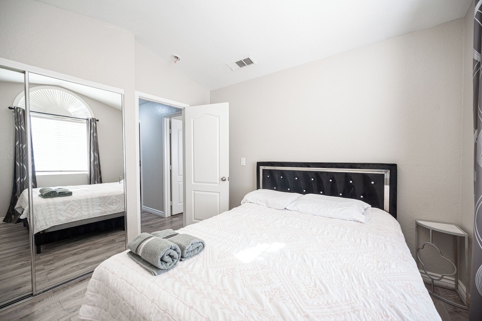 Habitación de hotel con una cama grande, un armario con espejo y una mesita de noche.