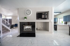 Ein modernes Interieur mit Kamin, einer Uhr und einer Küchenzeile.