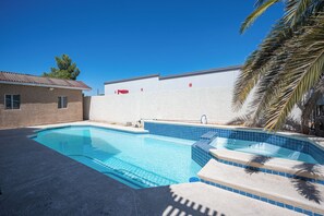 A swimming pool with clear blue water, surrounded by a white wall and a concrete deck. - Serene 5-bedrooms 3 bathrooms House with Pool in North Las Vegas (North Las Vegas)