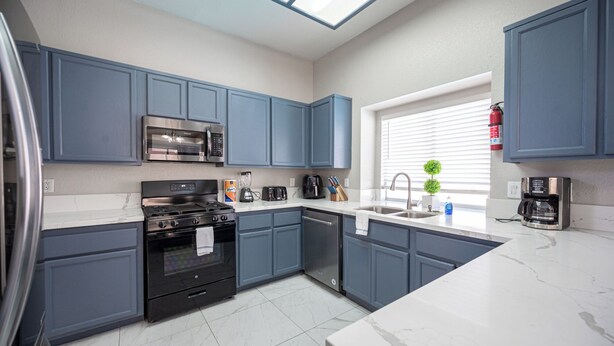 A modern kitchen with grey cabinets, a stainless steel microwave, a gas stove, and a dishwasher. - Serene 5-bedrooms 3 bathrooms House with Pool in North Las Vegas (North Las Vegas)