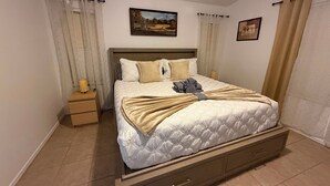 A neatly made bed with a headboard, a bedside table with a lamp, and two framed pictures on the wall. - Tutus House 🌞 Coldwater Springs, Avondale, AZ (Avondale)