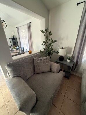 A living room with a grey sofa, a small table with a lamp, and a potted plant. - Tutu's House in Coldwater Springs, Avondale, AZ (Avondale)