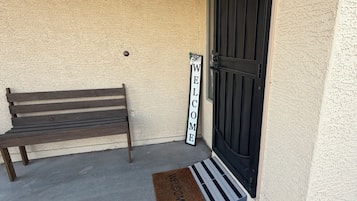 Un banc, une pancarte de bienvenue et une porte avec un paillasson.
