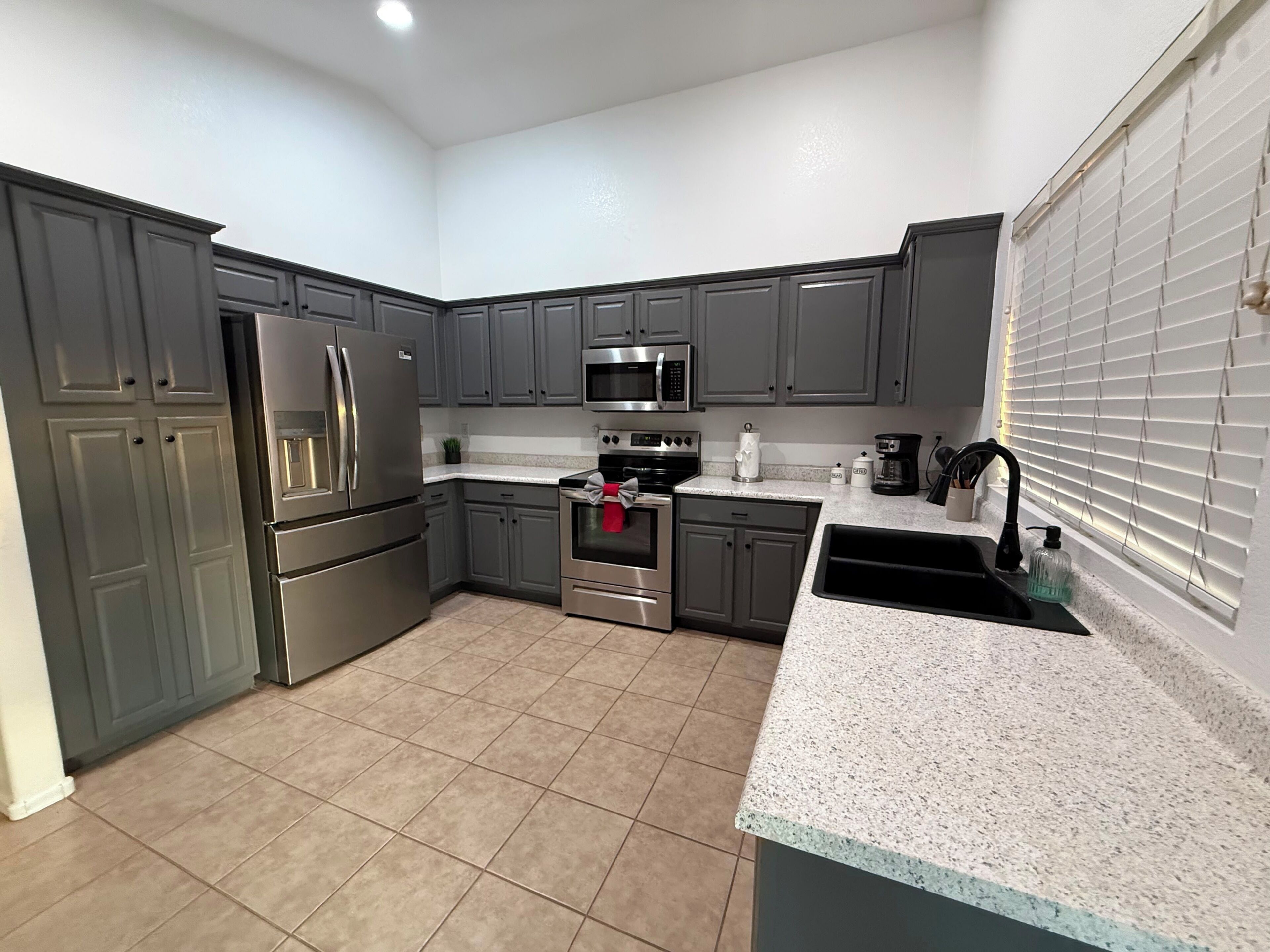 A kitchen with grey cabinets, stainless steel appliances, and a granite countertop.