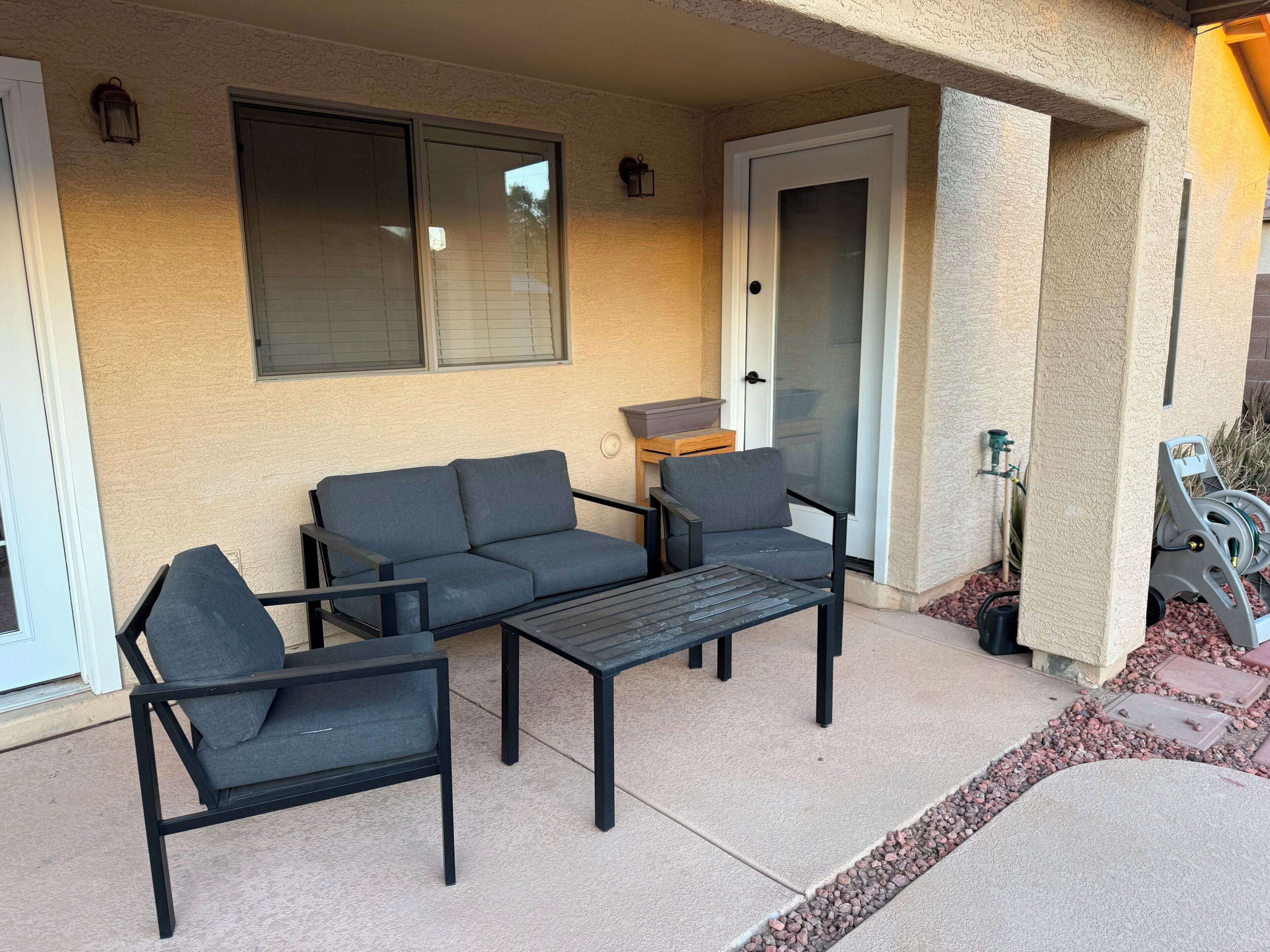 Un patio con un sofá, sillas y una mesa.