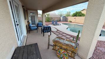 A covered patio area with a pool, outdoor furniture, and a decorative wooden chest.