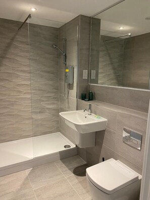 A modern bathroom with a walk-in shower, a sink, and a toilet. - Modern 1BR Apartment near MCR Stadiums (Stretford)