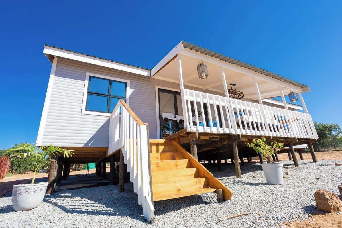 A two-story building with a balcony, wooden staircase, and a small garden area.