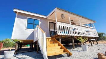 A two-story building with a balcony, wooden staircase, and a small garden area.
