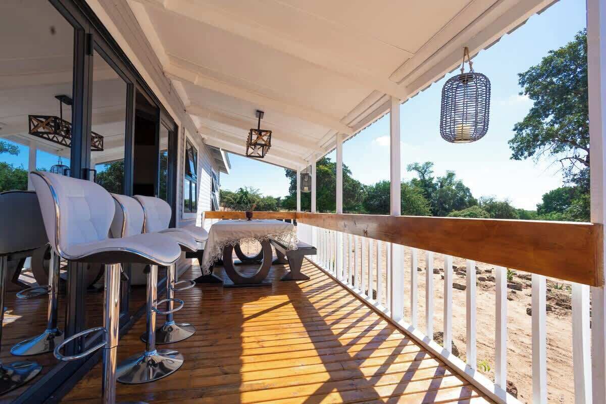 An outdoor deck with a wooden floor, white railings, and a table with chairs.