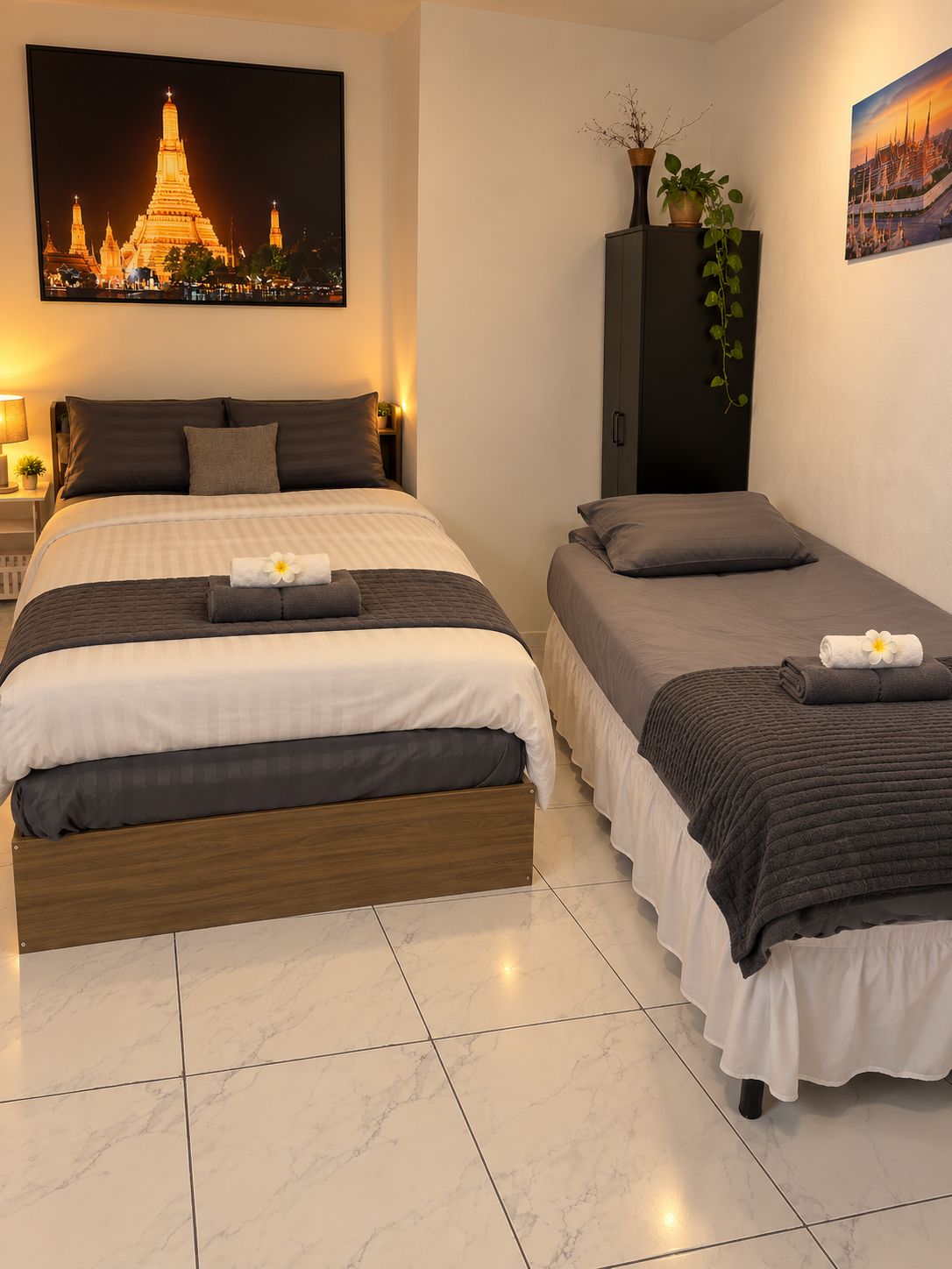 Une chambre d’hôtel avec un grand lit, un lit plus petit et une table de chevet avec une lampe.