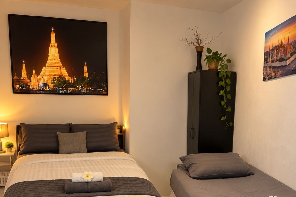 A hotel room with a large bed, a smaller bed, and a nightstand with a lamp.