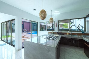 A modern kitchen with a central island, large windows, and a view of the outdoors. - Country house with a heated pool, terrace, and garden, accommodating up to 22 people (Jalisco)