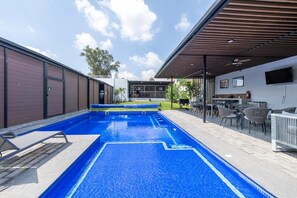 Une piscine dotée d’un espace détente abrité et d’un bar.