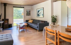 Ein gemütliches Wohnzimmer mit einer Couch, einem Couchtisch, einem Esstisch mit Stühlen, einem Kamin und einem großen Fenster.