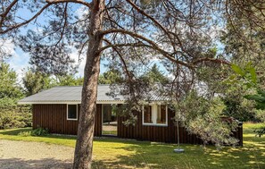 A wooden cabin with a metal roof, surrounded by trees and a grassy yard. - Lovely home in Løgstør with WiFi (Løgstør)