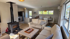 A modern living room with a fireplace, sofa, and dining area. - Comfy Haven in the Heart of Picton (Picton)